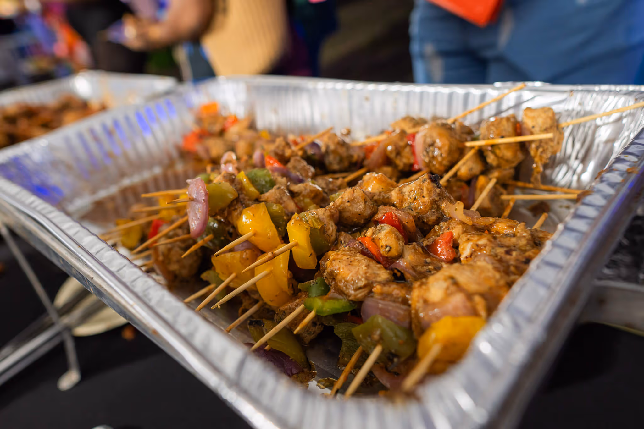 Tray of grilled meat and vegetable skewers with bell peppers and onions.